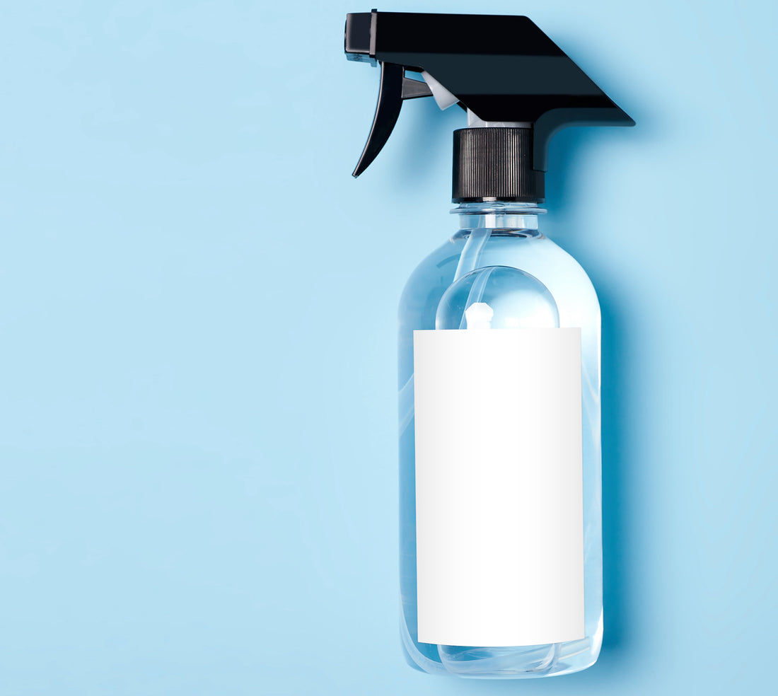 Un flacon spray contenant un liquide, sur fond bleu