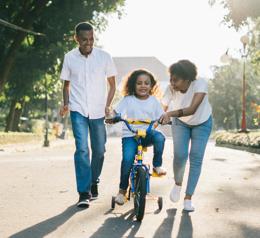 Une famille afro américaine qui apprend à leur fille à faire du vélo