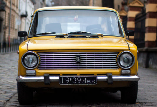 Une vieille voiture jaune dans une ville avec une plaque d'immatriculation noire
